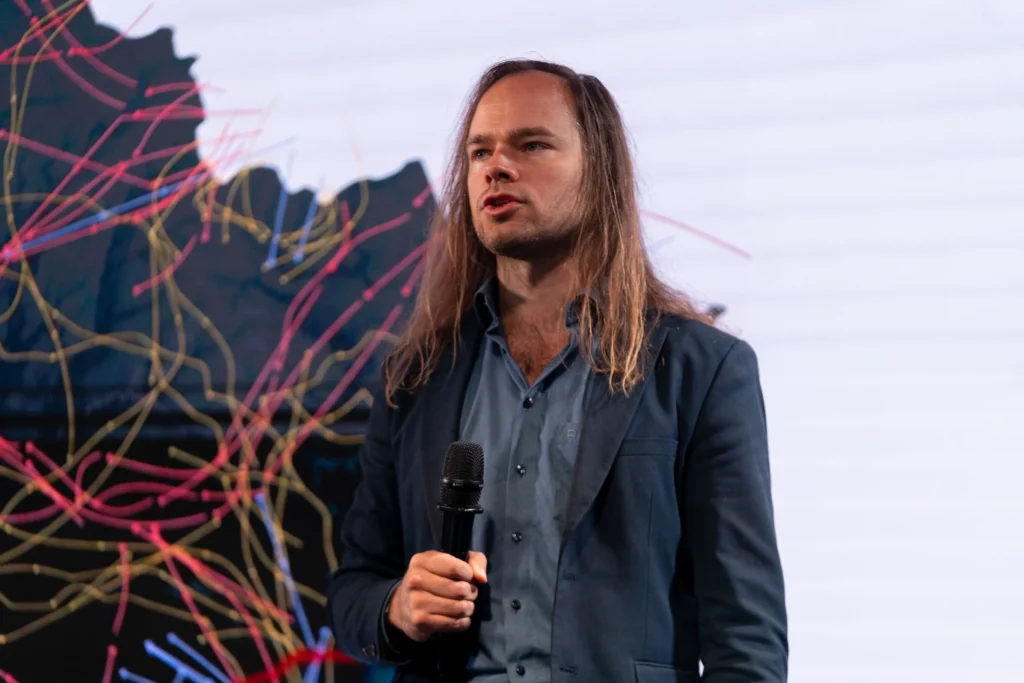 Мерайн Маркус на конференції виступає зі сцени з мікрофоном