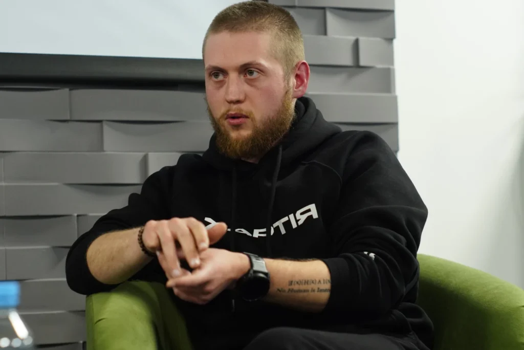 Чоловік у чорному худі дає інтерв'ю